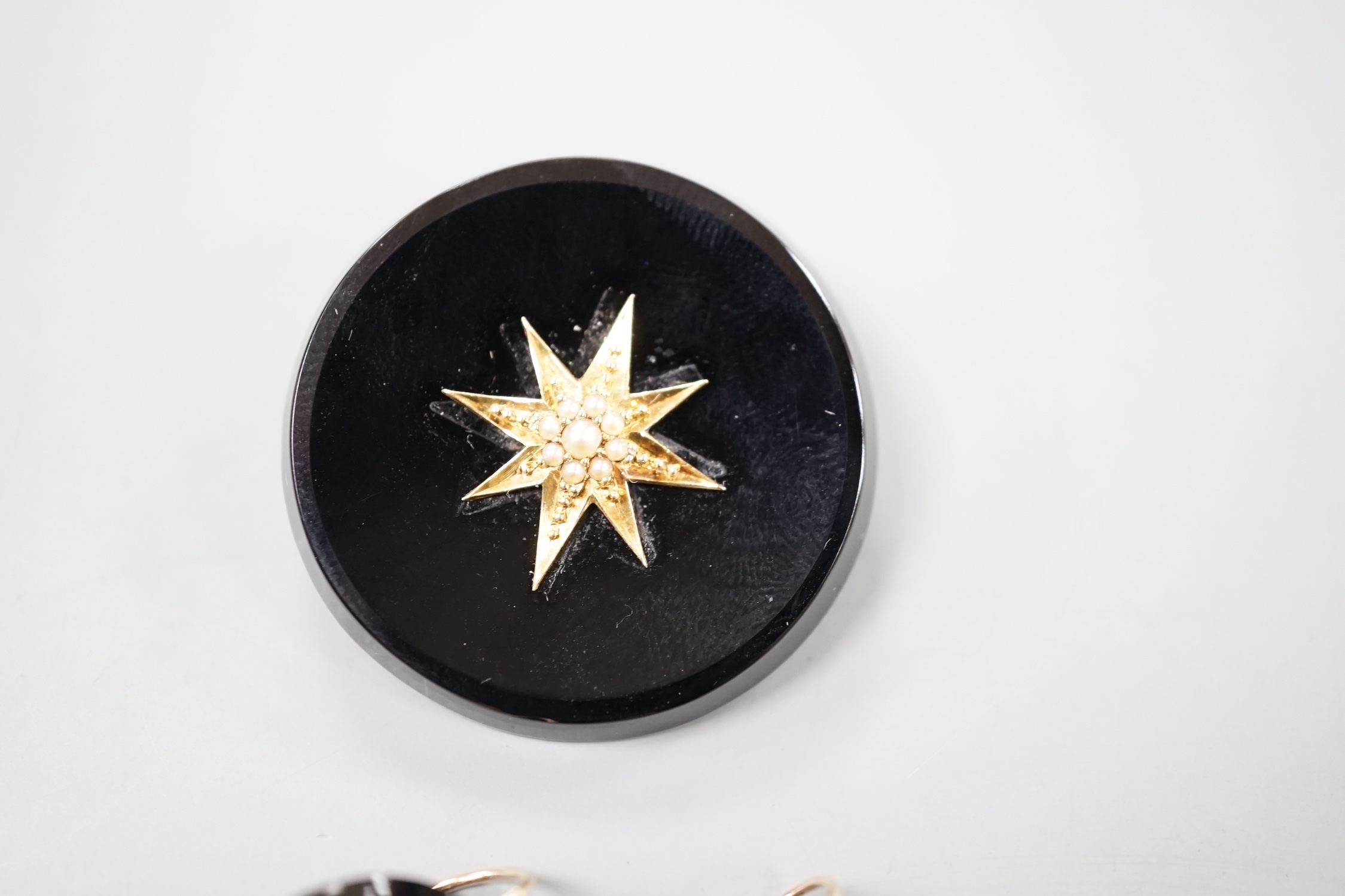 A late Victorian suite of yellow metal mounted black onyx and seed pearl mourning jewellery, coimprising a brooch, 33mm and pair of earrings.